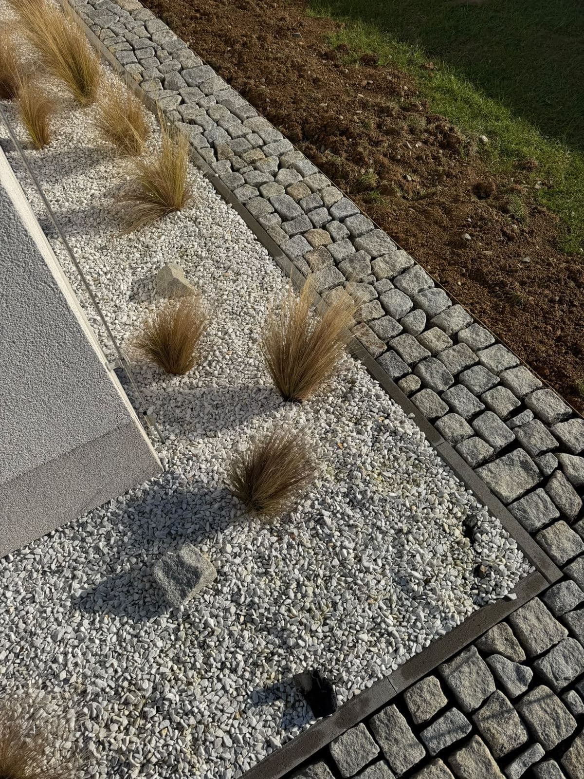 Detail lemu ze žulové kostky a záhonu z bílého štěrku s okrasnými travinami