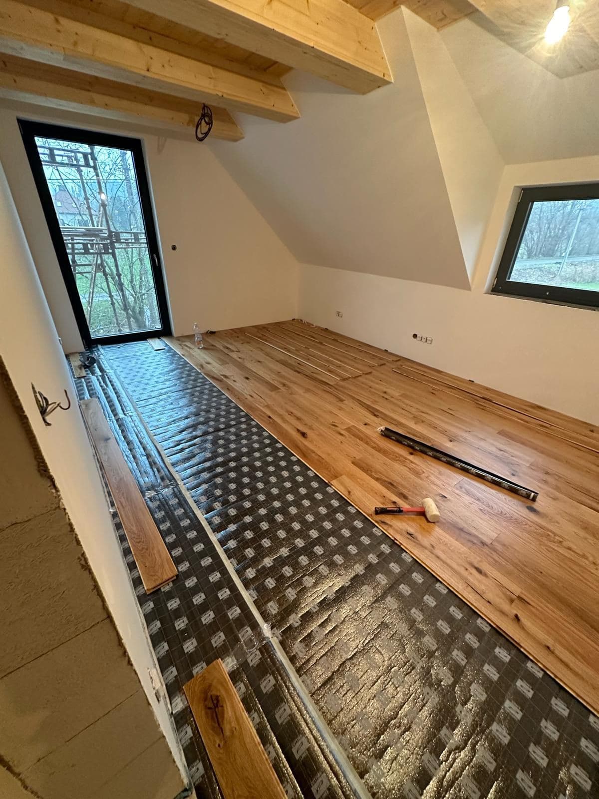 Pokládka masivní dubové podlahy v podkroví s přiznaným dřevěným stropem