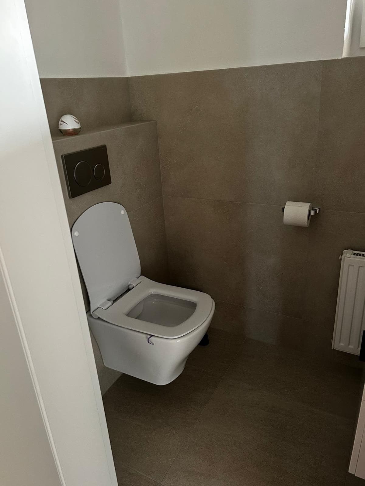 Samostatné WC se závěsnou keramikou a béžovým velkoformátovým obkladem