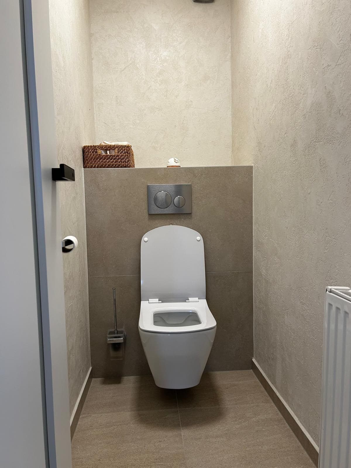 Úzké WC se závěsnou mísou, předstěnou a béžovým obkladem až ke stropu