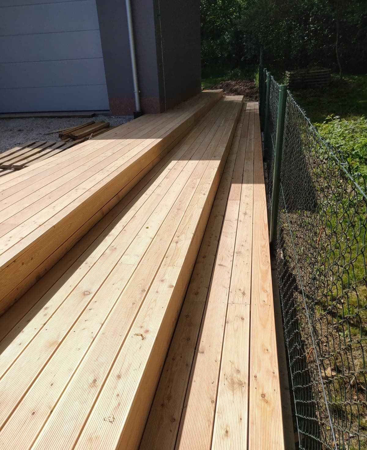 Modřínová prkna terasy podél domu a plotu, detail pokládky